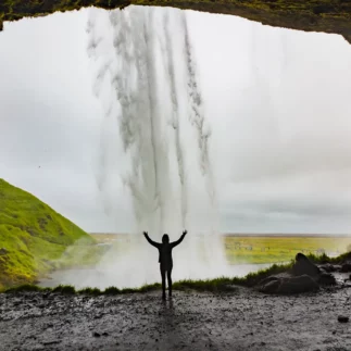 Woman standing in front of Seljalandsfoss waterfall in Iceland